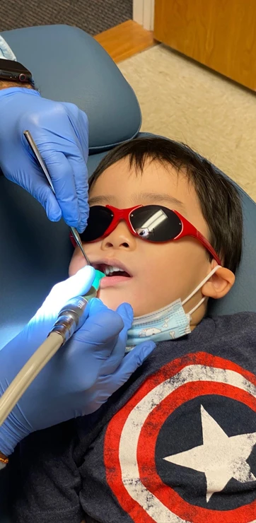 A pediatric patient lying on a dental exam chair during an exam